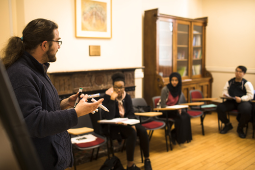 Image of lecturer teaching three students at desks